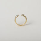 Gold and crystal accented open claw ring featuring two snake heads with green crystal eyes green eyes