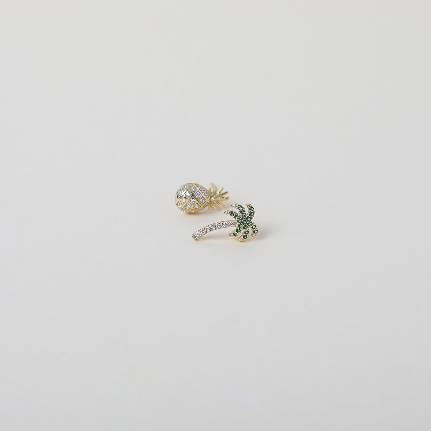 Mismatched gold and green crystal embellished Palm Tree and crystal embellished pineapple duo earring set.