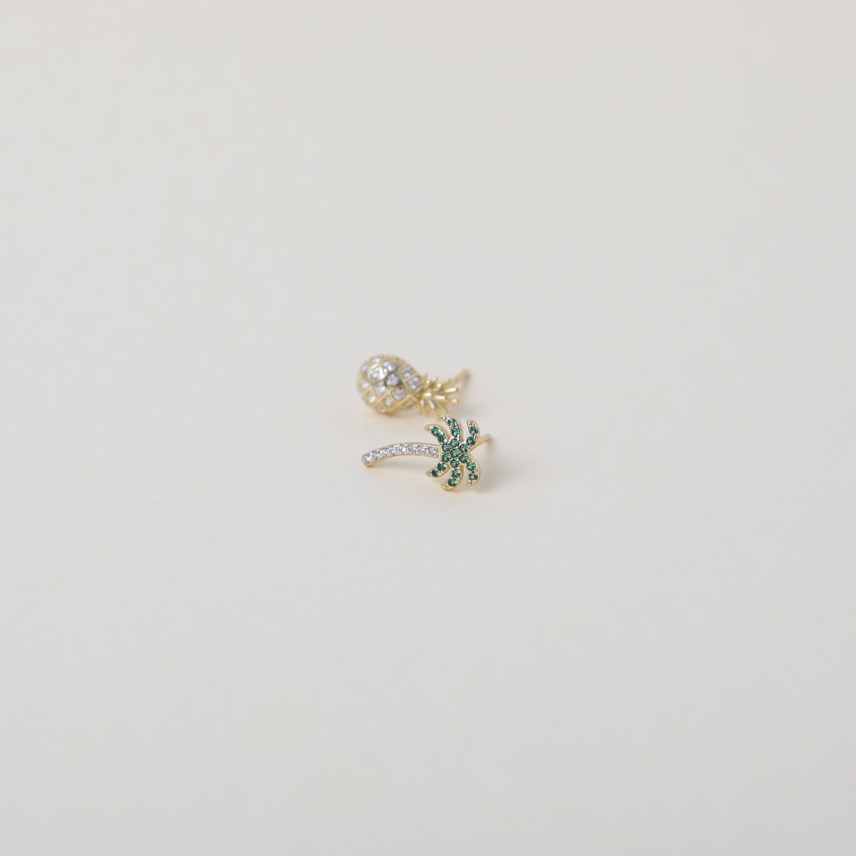 Mismatched gold and green crystal embellished Palm Tree and crystal embellished pineapple duo earring set.