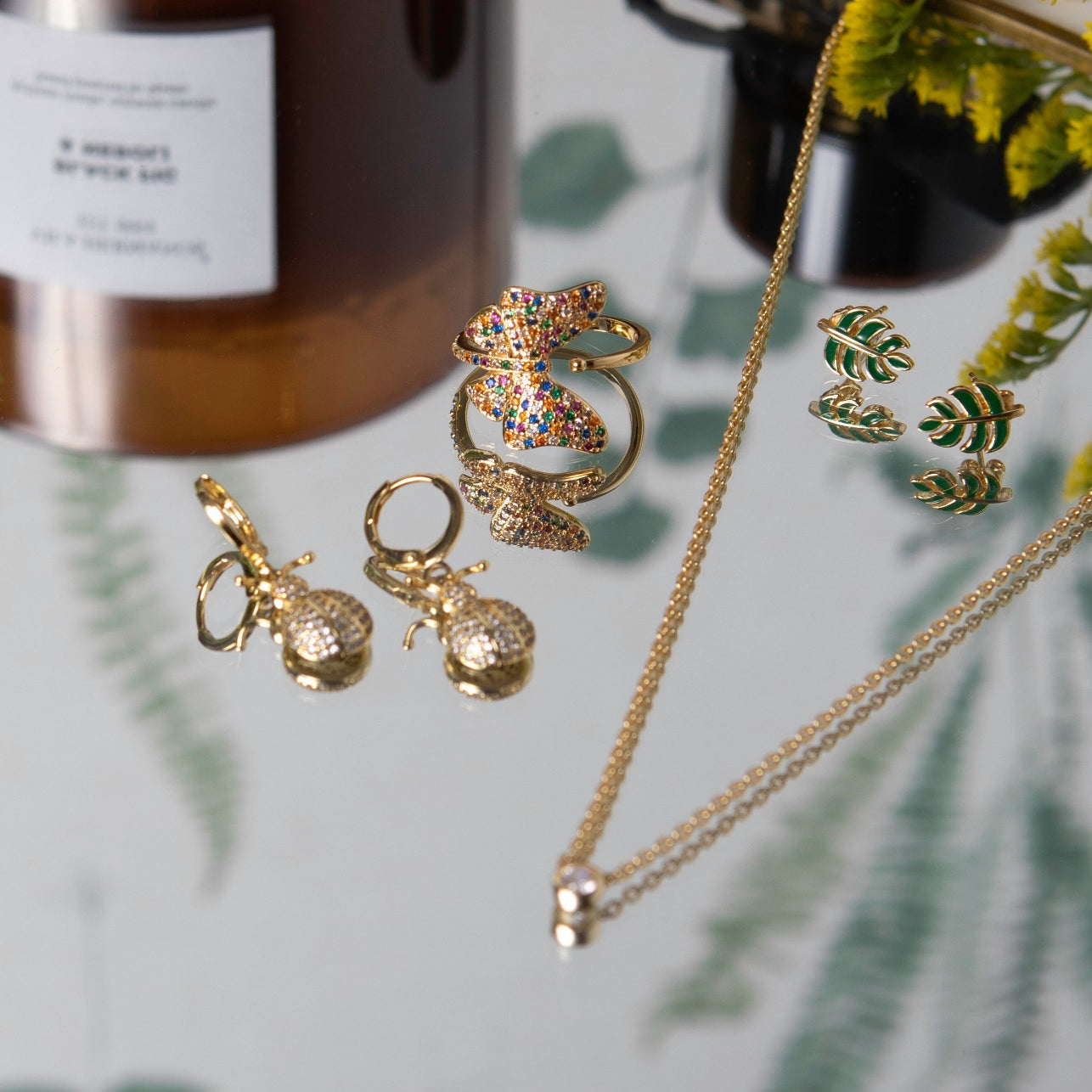 gold and green enamel leaf studs in a lifestyle image