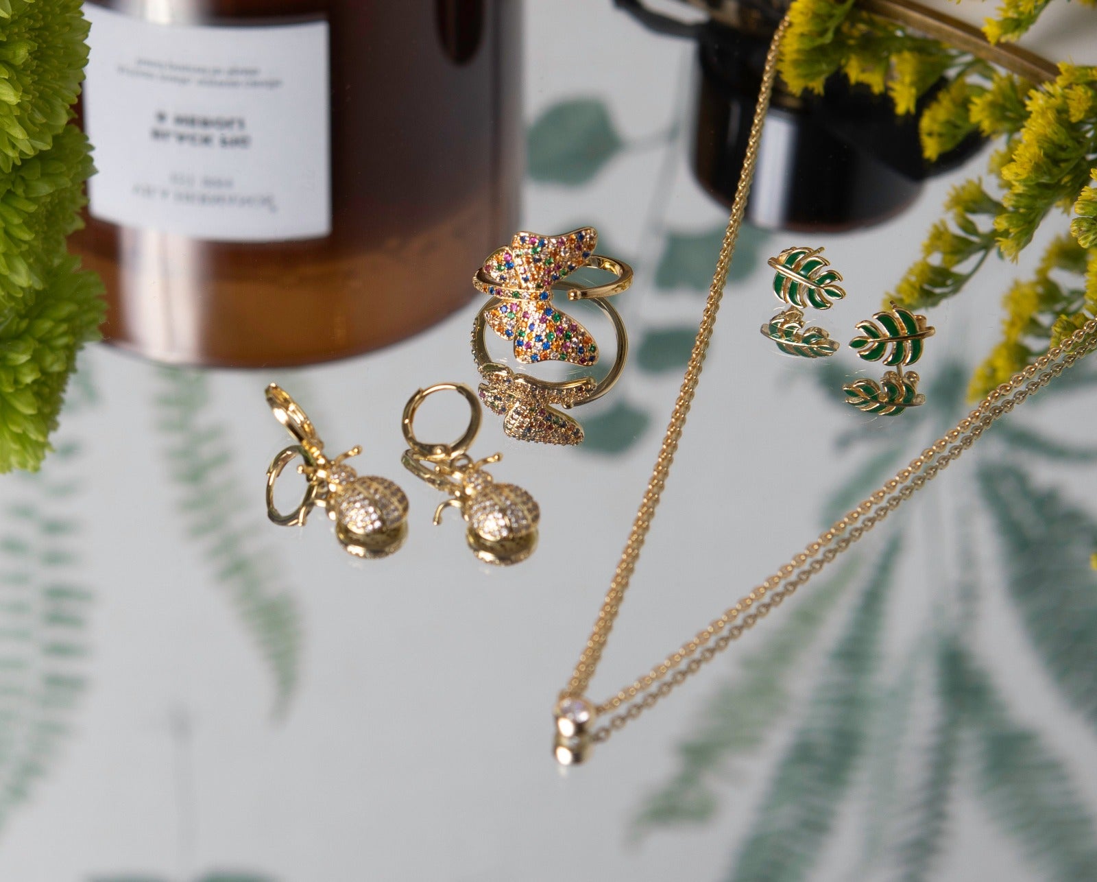 gold and green enamel leaf studs in a lifestyle image